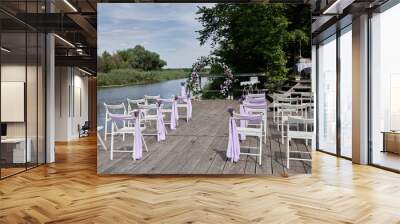 Place for wedding ceremony on wood terrace by river, copy space. Circle wedding arch decorated with flowers and chairs on each side of archway. Wedding setting Wall mural