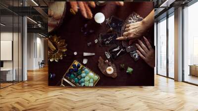 Top view of a tarot card spread. A woman points to one of the cards on her witch altar with several semi-precious stones on the table Wall mural