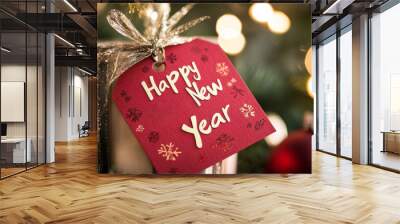 A beautifully wrapped gift with a festive New Year tag, surrounded by holiday decorations and glowing lights, celebrating the joyous occasion Wall mural