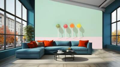 Colorful lollipops leaning against a green wall and a pink background. Minimal candy lay out concept Wall mural