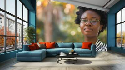 Woman with curly hair and glasses posing outdoors in natural light during daytime Wall mural