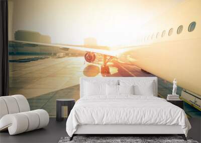 Generic airplane on terminal gate ready for takeoff - Modern international airport at sunset - Concept of emotional travel around the world - Wide angle distortion with enhanced sunshine lens flare Wall mural