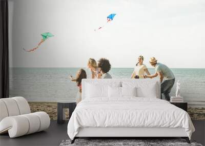 Group of happy families with parent and children playing with kite at beach vacation - Summer joy carefree concept with mixed race people having fun together at sunset  - Bright vintage  filter Wall mural