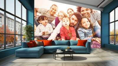 Happy multiracial families taking selfie at beach making funny faces - Multicultural happiness joy and love concept with mixed race people having fun outdoor at sunset - Bright pastel backlight filter Wall mural