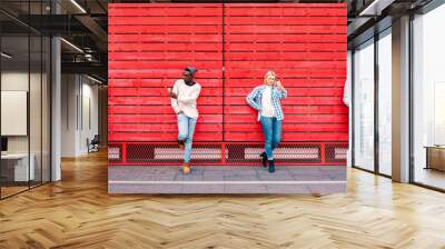 Multicultural friends group using smartphone by red wooden background - Technology and urban lifestyle concept with millenial people sharing content online with modern mobile phones - Vivid filter Wall mural