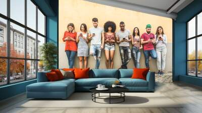 Multiracial friends using smartphone against wall at university college backyard - Young people addicted by mobile smart phone - Technology concept with always connected millennials - Filter image Wall mural