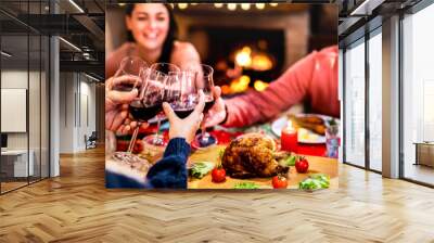 People toasting red wine having fun at Christmas dinner reunion - Holiday celebration concept with happy family sharing winter time together at home supper feast - Warm filter with focus on glasses Wall mural