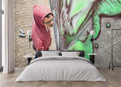 Street artist painting colorful graffiti on generic wall - Modern art concept with urban guy performing and preparing live murales with green aerosol color spray - Sunny afternoon neutral filter Wall mural