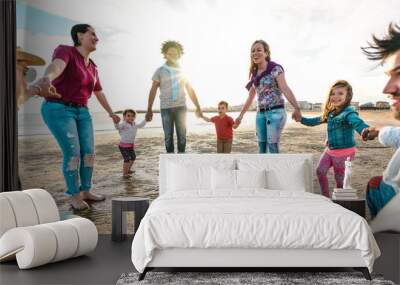 View point of young families dancing at beach on ring around the rosy style - Lifestyle joy concept with mixed race people having fun moment holding hands - Vivid backlight filter with sunshine halo Wall mural