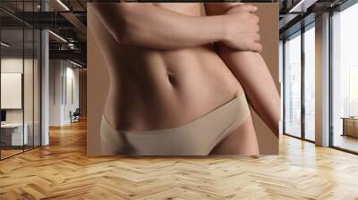 Thin young woman in underwear on beige background Wall mural