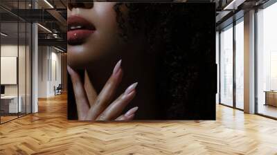 Woman's lips and hand in close-up. Long nails, wet lip gloss, dark skin Wall mural