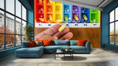 Hand holds medical pill near seven days box for pills  Wall mural