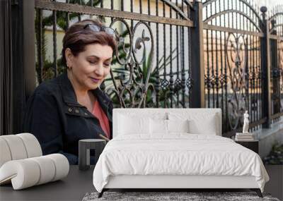 Wrought Fence. Woman with pencil and notebook leaning against Wrought iron Fence Wall mural