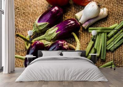 Close up of vegetables for a spicy Indian lunch i.e. Egg plant,Solanum melongena,Tomato,Solanum lycopersicum and spring onions,Allium fistulosum on a gunny background. Wall mural