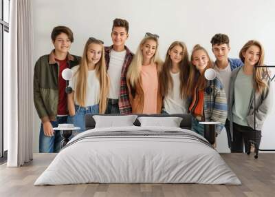 Group of young teenagers in casual attire on white background. Teenagers are smiling and embracing each other. The group is diverse, consisting of boys and girls of different ages and ethnicities. Wall mural