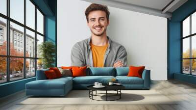 Handsome caucasian male with casual attire, crossed arms, cheerful expression. He is smiling at camera with confidence, positivity. Young adult with blond hair, beard, wearing stylish clothes. Wall mural