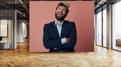 Handsome man with beard wearing business suit, arms crossed, and king crown. Confident, cheerful, and joyful expression. Man smiling and laughing hard out loud, enjoying funny joke. Wall mural