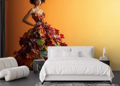 a girl is posing in a long dress made of orange, green and brown autumn leaves, against orange background. Fall fashion style Wall mural