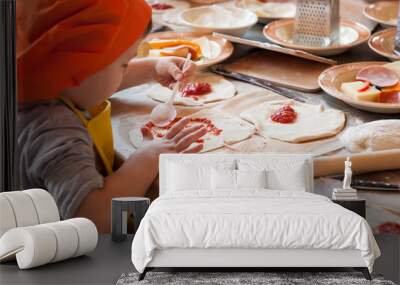 boy making homemade pizza working in the kitchen in chefs uniforms and smear sauce the base Wall mural