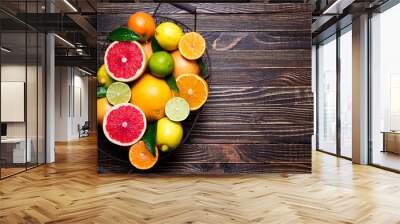 Fresh citrus fruits in basket. Orange, grapefruit, lemon, lime, tangerine on dark wooden table. Assorted fresh citrus fruits with leaves. Top view and copy space Wall mural