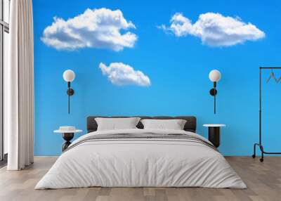 Three isolated white clouds in a clear blue sky with space for text. Wall mural