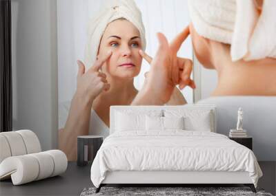 Middle aged woman looking at wrinkles in mirror. Plastic surgery and collagen injections. Makeup. Macro face. Selective focus on the face. Wall mural