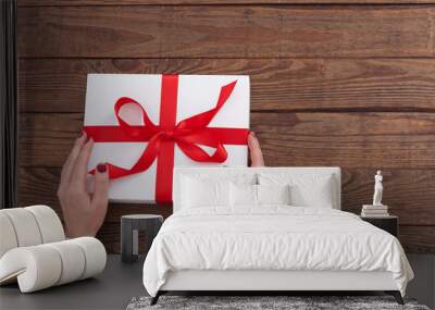 Woman holding presents gift box laid on wooden table background Wall mural