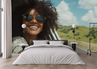 A woman with curly hair wearing sunglasses is leaning out of the open window of an old white car, Wall mural