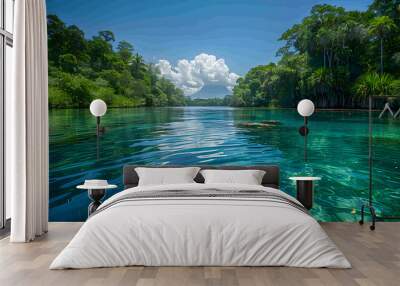 A serene nature lagoon with clear blue water surrounded by lush vegetation, the sky clear and blue above Wall mural