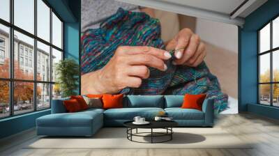 Close up of hands of unrecognizable woman knitting handmade clothes with spokes using  wool yarn. Concept of leisure activity.Knitting from yarn on  coarse spokes. Wall mural