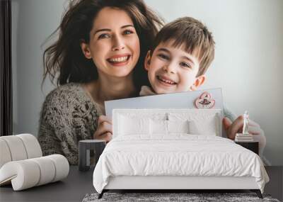 Beautiful smiling young mother with her son holding a sign that says happy mother's day. Wall mural