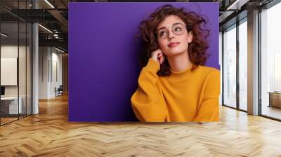 Fashionable woman in autumn sweatshirt poses by empty poster on stylish purple background Wall mural