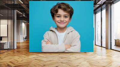 Happy kid with arms crossed smiling on blue background, isolated cheerful child portrait Wall mural