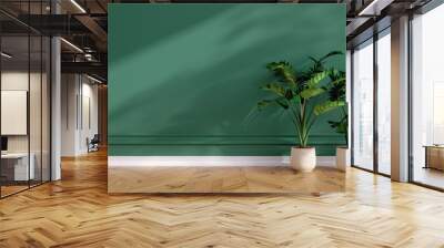 Elegant green interior featuring a blank wall, warm wooden flooring, and two decorative plants, creating a serene and inviting atmosphere for relaxation and style. Wall mural