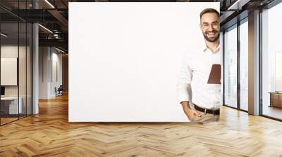 Confident business man holding digital tablet and smiling, standing against white background Wall mural