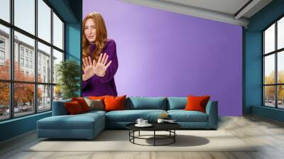 Gross take it away. Portrait of disgusted redhead woman step back and waving palms over body in refusal and no gesture grimacing and squinting from bad smell or aversion over purple wall Wall mural