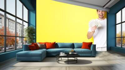 Happy handsome guy pointing finger at money, concept of credit and loan, standing over yellow background Wall mural