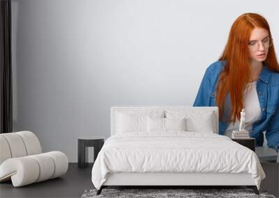 Inspiration, work and art concept. Focused busy cute redhead female in glasses, writing down notes from laptop, use useful website, online course to learn drawing, white background Wall mural