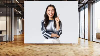 Lifestyle, people emotions and casual concept. Excited smart and creative asian female coworker have suggestion, add idea, raising index finger to say thought or plan, standing white background Wall mural