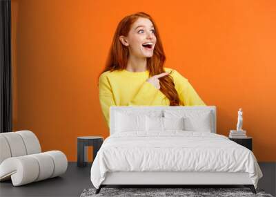 Look at that, wow. Impressed and fascinated, astonished cute redhead woman stare and pointing left with excited, happy smile, shoppaholic adore winter holiday sales, express interest and admiration Wall mural