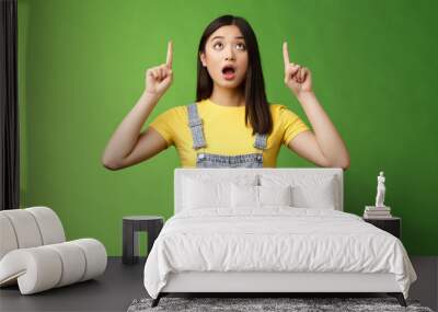 Omg look shocking price fall. Stunned speechless amazed asian girl drop jaw, wondering what happening upstairs, pointing lookin up impressed, staring surprised stand green background Wall mural