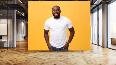 Portrait of delighted African American male with positive smile, white perfect teeth, looks happily at camera, being successful enterpreneur, wears white t shirt. Wall mural