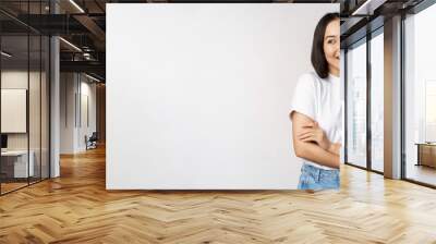 Portrait of happy asian woman smiling, posing confident, cross arms on chest, standing against studio background Wall mural