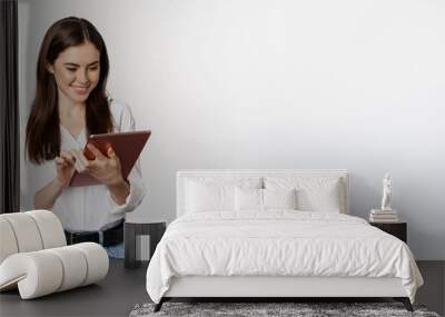 Portrait of smiling corporate woman looking at digital tablet, working, standing over white background Wall mural