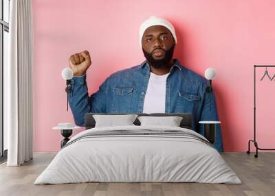 Serious and confident african-american male activist, raising fist, support Black lives matter BLM movement, fight for human rights against racism, pink background Wall mural