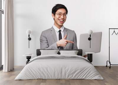 Waist-up portrait of successful pleased young asian businessman bragging about his new program, create good project, standing white background in suit, pointing at laptop display with approval Wall mural