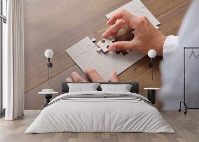 Folding puzzle hand parts on a wooden table Wall mural