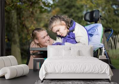 Disabled girl in a wheelchair relaxing outside / Disabled  girl in a wheelchair relaxing outside together with a care assistant Wall mural