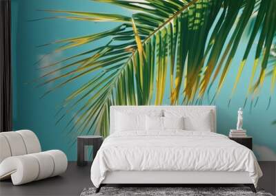 Close-up shot of a palm leaf against a bright blue sky Wall mural