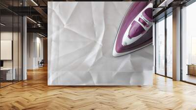 Lilac iron on a piece of white crumpled fabric. ironing clothes. household electrical appliances. view from above. Wall mural